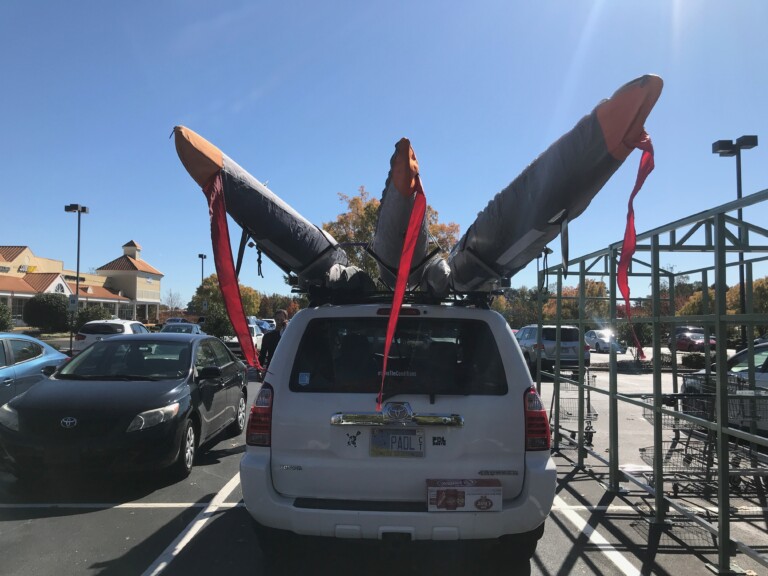 This is a photo a car loaded with outrigger canoes leaving a paddle race.